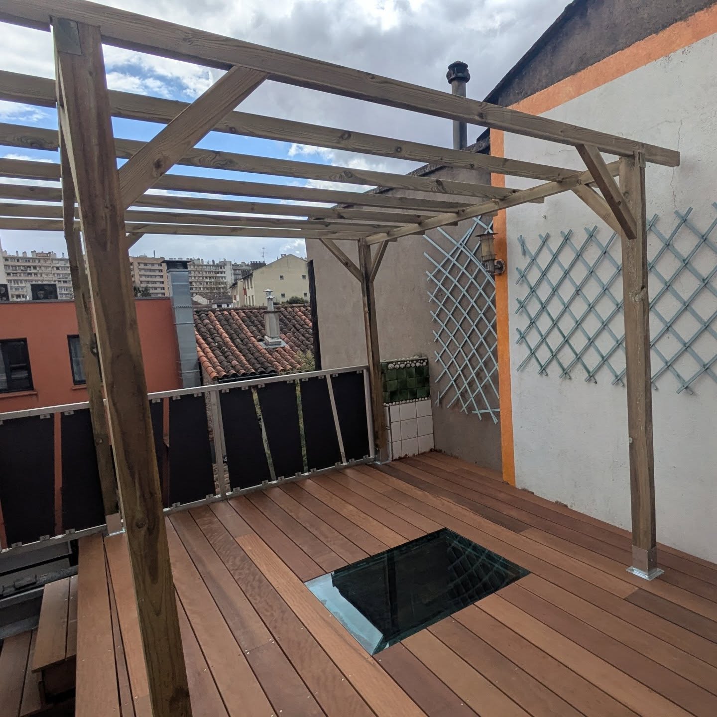 Terrasse en itauba construite au-dessus d'un toit en tuile.
Création d'une pergola sur la terrasse.